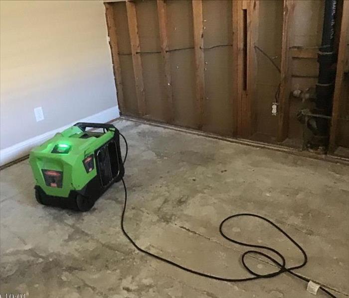residential room with carpet completely removed and dehumidifier present 