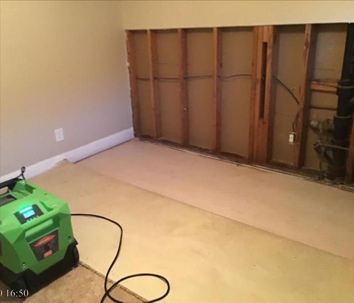 residential room with carpet peeled back and dehumidifier present