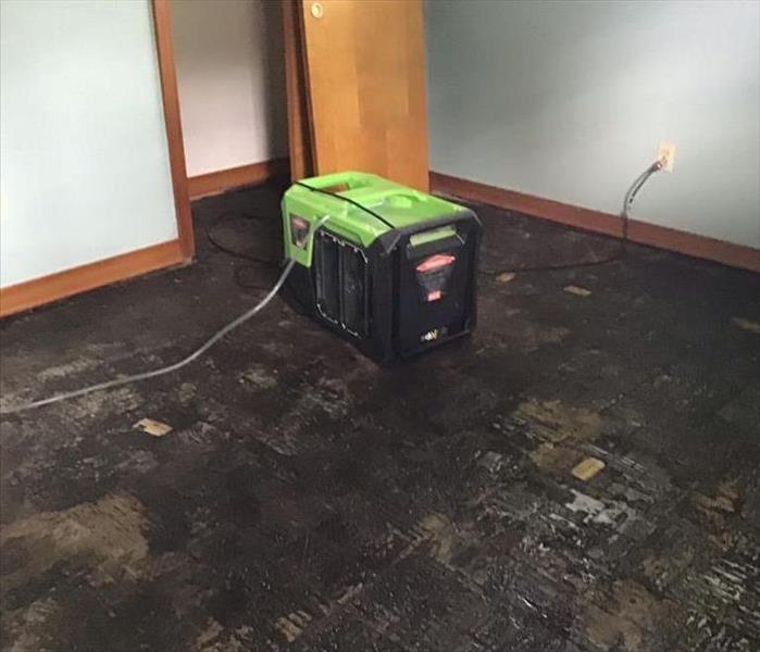 Floors ripped up in bedroom with SERVPRO equipment on the floor 
