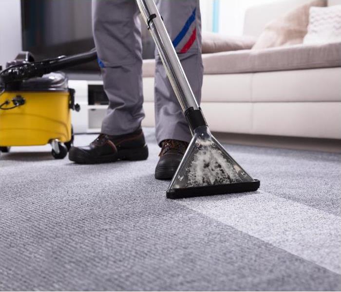 Legs of man cleaning carpet with professional device