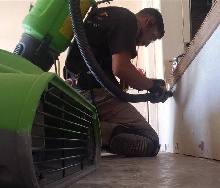 Male SERVPRO employee on his knees performing mitigation 