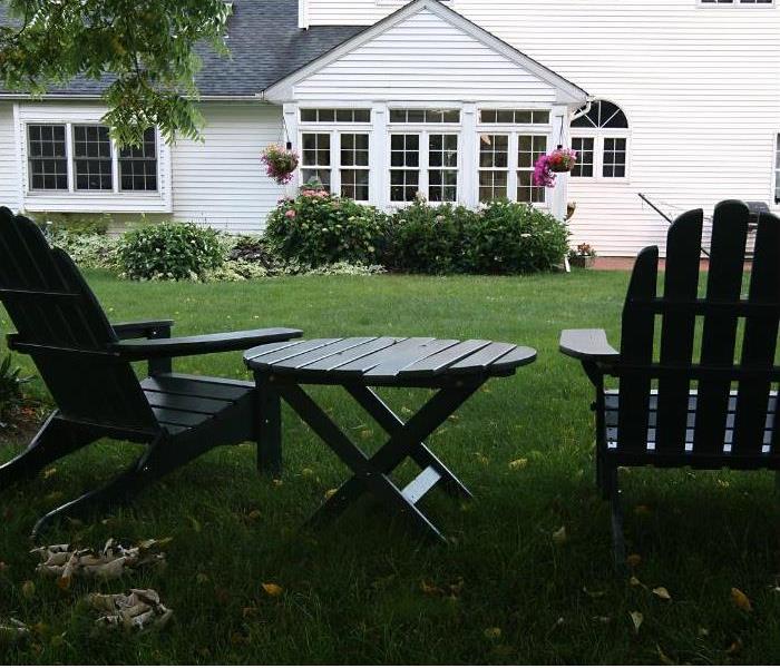 backyard of white house with two chairs and a table